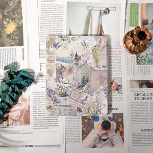 May include: A journal with a collage design featuring lavender, floral elements, and vintage postcards. The cover showcases shades of purple, white, and green, creating a romantic and artistic aesthetic.
