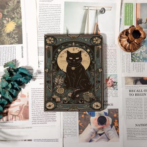 Peut inclure: Illustration carrée d'un chat noir devant une lune, entouré de fleurs. Le style est vintage, art nouveau, avec des tons vert foncé et or. L'œuvre mesure environ 15 cm x 15 cm.