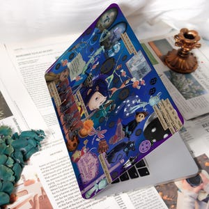 May include: A laptop skin featuring a collage of illustrations and text from the animated film, "Coraline." The design is predominantly blue with images of characters, buttons, and other elements from the movie. The text includes phrases like "Pink Palace apartments" and "Be careful what you wish for."