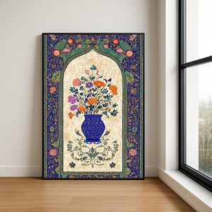 Puede incluir: Impresión artística enmarcada con un jarrón azul lleno de flores coloridas. El jarrón se encuentra sobre un fondo crema dentro de un arco decorativo. El marco y el borde son de color azul oscuro con motivos florales y de aves.