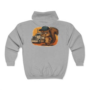 May include: A light gray zip-up hoodie featuring a cartoon squirrel wearing a cap and standing next to a semi-truck. The squirrel has an angry expression and the word "COFFEE" is visible. The design is printed on the back of the hoodie.