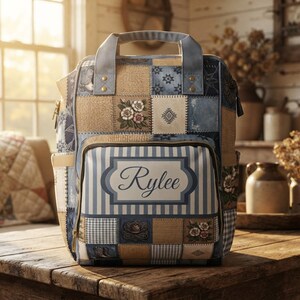 May include: A backpack featuring a patchwork design of blue, tan, and white squares with floral, star, and cowboy boot patterns. The front pocket displays a rectangular label with the name Rylee in script font over a blue and white striped background.