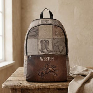 May include: A backpack featuring a patchwork design with illustrations of cowboy boots, a bull skull, and a lasso. The lower section is dark brown with a graphic of a person riding a bucking horse and the name WESTON printed in white lettering.