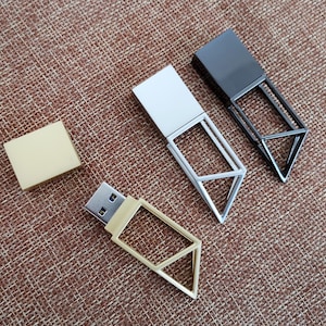 Può includere: Quattro chiavette USB con involucri metallici di diversi colori e design geometrici. Le chiavette sono su una superficie di tessuto marrone.