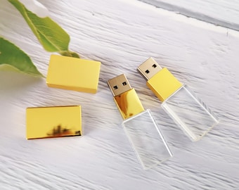 Könnte beinhalten: Zwei goldene USB-Sticks mit durchsichtigen Kristallgehäusen. Ein Stick ist geschlossen, der andere ist geöffnet und zeigt den USB-Stecker.