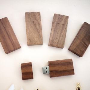 May include: Five wooden USB flash drives in various sizes and shapes. The drives are made of dark brown wood and have a natural finish. One drive is plugged into a computer.