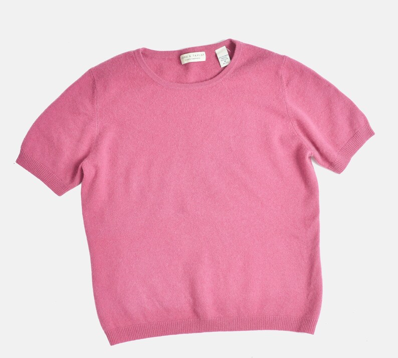 Flat view of a vintage 1990s or Y2K pink cashmere sweater. Fitted, t-shirt style. Short sleeves. Crewneck. Displayed on a dress form with jeans.
