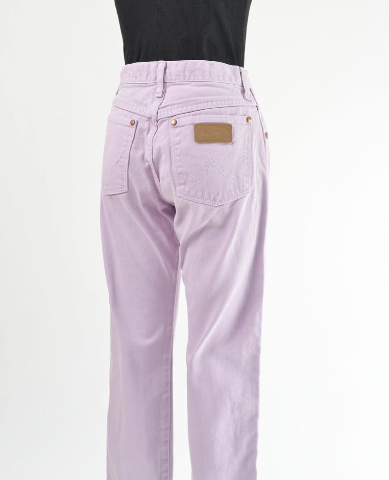 Vintage 90s western style Wrangler jeans. Light purple denim. High waisted. Straight legs. Displayed on dress form with a black t-shirt. Side back view.