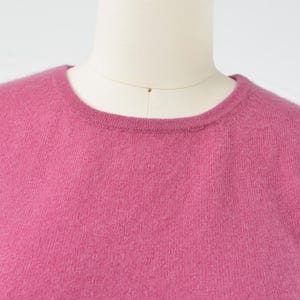 Neckline view of a vintage 1990s or Y2K pink cashmere sweater. Fitted, t-shirt style. Short sleeves. Crewneck. Displayed on a dress form with jeans.