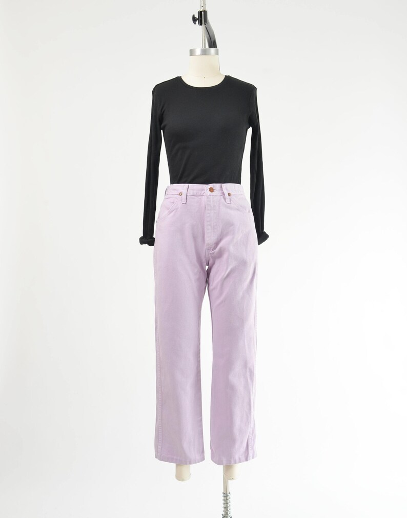 Vintage 90s western style Wrangler jeans. Light purple denim. High waisted. Straight legs. Displayed on dress form with a black t-shirt.