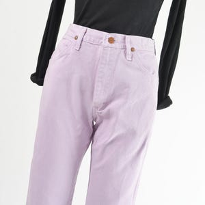 Vintage 90s western style Wrangler jeans. Light purple denim. High waisted. Straight legs. Displayed on dress form with a black t-shirt. Close up view of waistline.