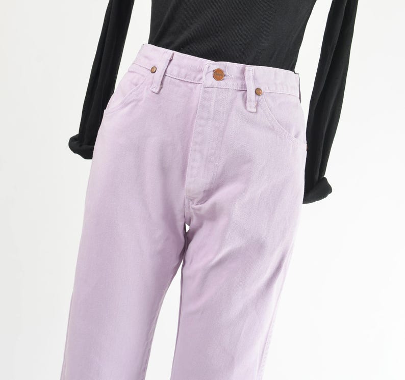 Vintage 90s western style Wrangler jeans. Light purple denim. High waisted. Straight legs. Displayed on dress form with a black t-shirt. Close up view of waistline.