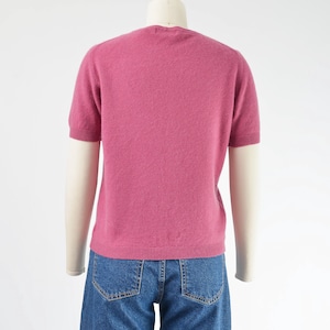 Back view of a vintage 1990s or Y2K pink cashmere sweater. Fitted, t-shirt style. Short sleeves. Crewneck. Displayed on a dress form with jeans.
