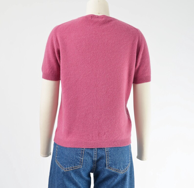 Back view of a vintage 1990s or Y2K pink cashmere sweater. Fitted, t-shirt style. Short sleeves. Crewneck. Displayed on a dress form with jeans.