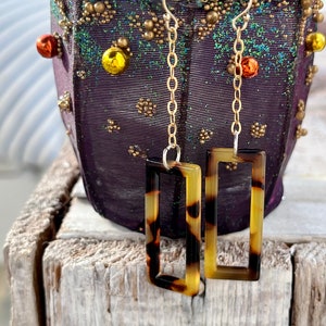 May include: A pair of gold chain earrings with rectangular tortoise shell dangles.
