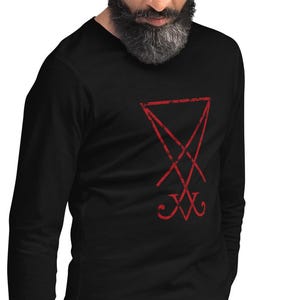 Peut inclure: Un t-shirt noir à manches longues avec un motif rouge vieilli du sceau de Lucifer imprimé sur la poitrine. Le vêtement présente une encolure en V et des manches longues avec des poignets ajustés, offrant un design sobre et épuré.