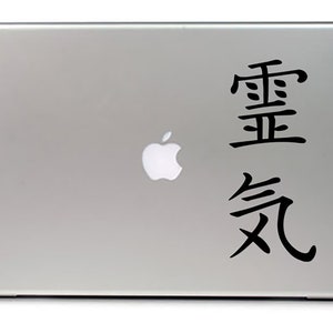 May include: A silver laptop with a black Apple logo and a black sticker with the Chinese characters "重要" and "気" on the back.