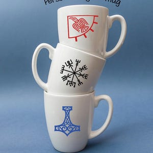 K&ouml;nnte beinhalten: Drei wei&szlig; gestapelte Keramikbecher. Der oberste Becher zeigt eine rote Rabengrafik, der mittlere Becher ein schwarzes Vegvisir-Symbol und der untere Becher ein blaues Mjolnir-Design. Der Text Personalize your mug steht oben im Bild.