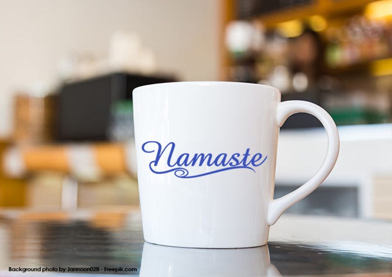 Puede incluir: Taza de cer&aacute;mica blanca con una inscripci&oacute;n azul en cursiva que dice "Namaste".