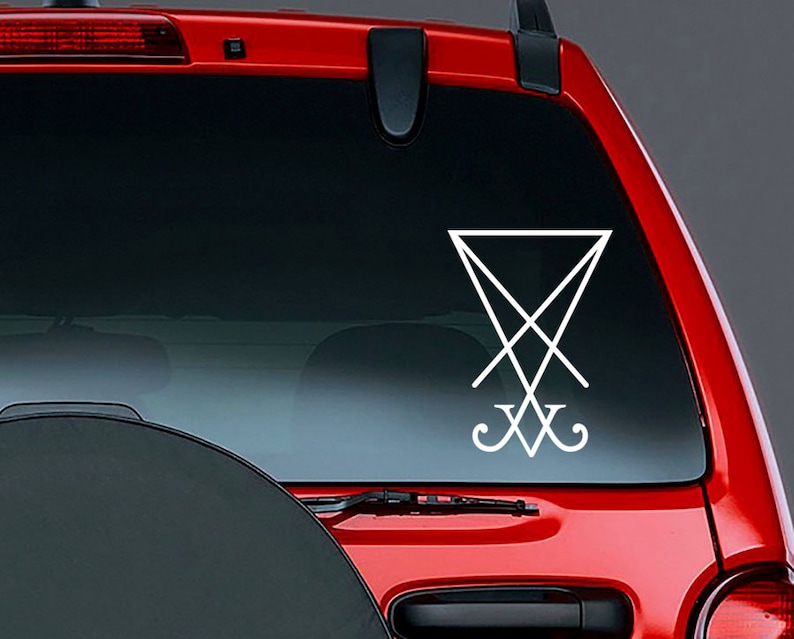 May include: A white vinyl sticker of the sigil of Satan, a pentagram with an inverted cross inside, on the back window of a red car.