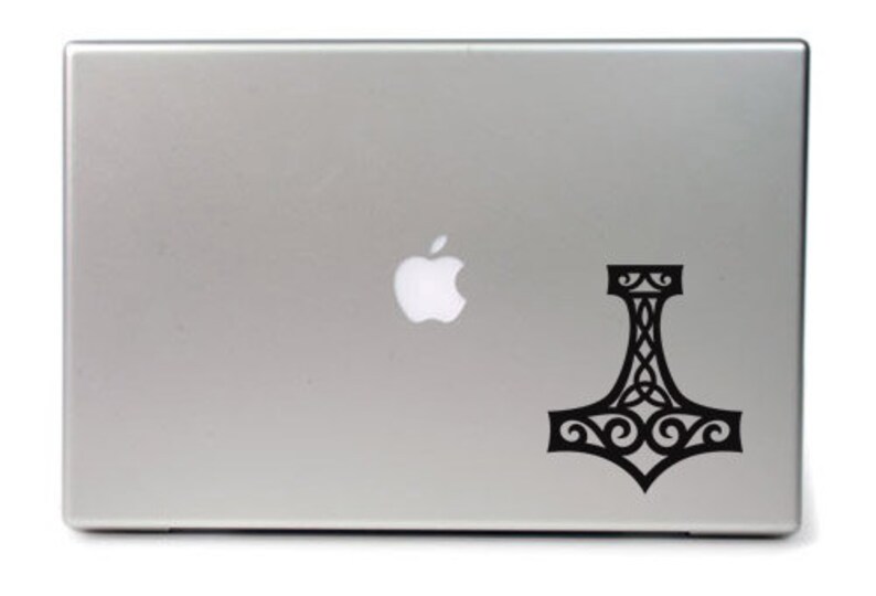 K&ouml;nnte beinhalten: Ein silberfarbener Laptop mit einem schwarzen Vinyl-Aufkleber auf dem Deckel. Der Aufkleber zeigt einen stilisierten Mjolnir, oder Thors Hammer, mit komplizierten Knoten- und Schn&ouml;rkelmustern, die in das Design des Hammers integriert sind.