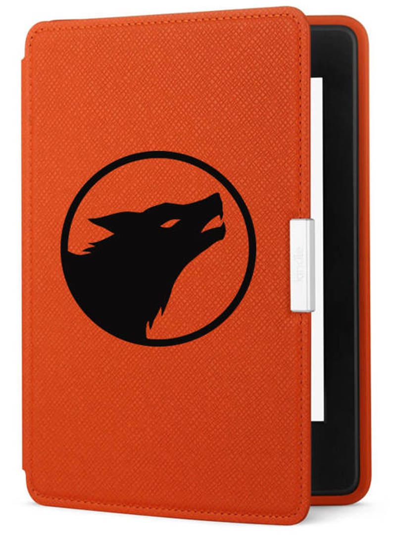 K&ouml;nnte beinhalten: Orangefarbene Kindle E-Reader-H&uuml;lle mit einer schwarzen Wolfssilhouette-Grafik in einem Kreis. Die H&uuml;lle hat eine strukturierte Oberfl&auml;che und ein Kindle-Logo an der Seite.