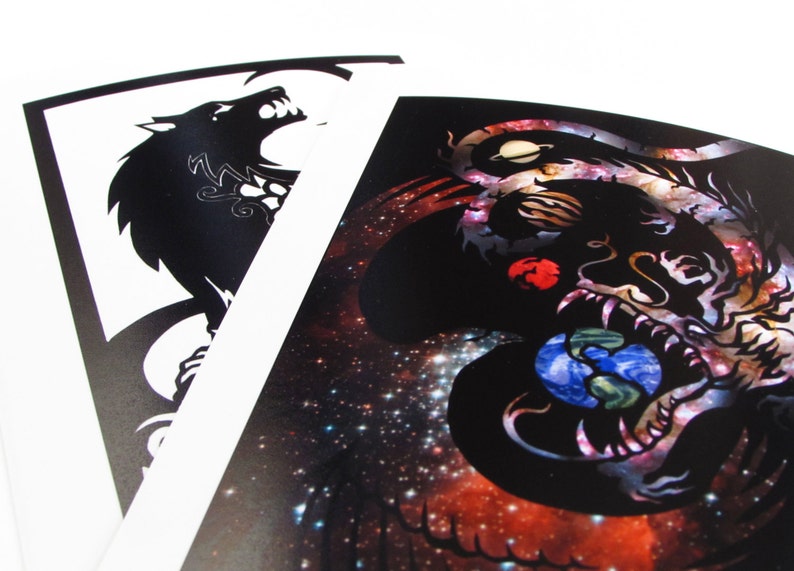 May include: Two black and white illustrations on white cardstock. The left illustration is a wolf howling at the moon. The right illustration is a dragon with a galaxy background.