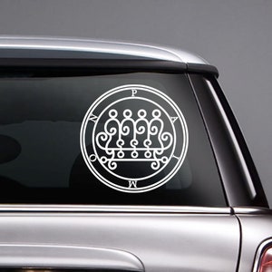 May include: A white vinyl decal of a sigil with the letters "P.A.M.W." around the outside. The sigil is a circle with a crown-like design inside.