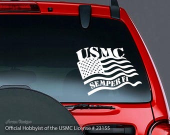 May include: White vinyl decal featuring the USMC emblem, a waving American flag, and the words "USMC" and "Semper Fi." The decal is displayed on a red vehicle window.