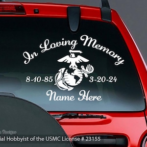 May include: White vinyl decal for a vehicle window, featuring the words "In Loving Memory" above a Marine Corps emblem. Includes dates 8-10-85 and 3-20-24, with space for a name. The decal is from Arwen Designs, Official Hobbyist of the USMC.
