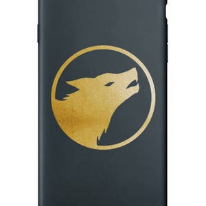 K&ouml;nnte beinhalten: Eine schwarze Handyh&uuml;lle mit einer goldenen Wolfskopf-Silhouette in einem Kreis.