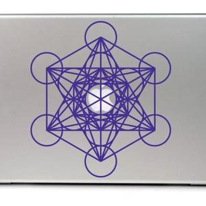 May include: A silver laptop with a purple geometric design sticker on the lid. The design is a complex pattern of overlapping circles and lines, creating a star-like shape.
