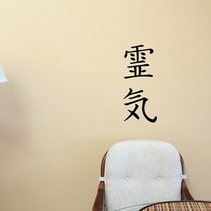 May include: A black and white wall decal with the Chinese characters for "important" and "air" in a vertical arrangement. The decal is on a beige wall with a white lamp and a white chair in the background.