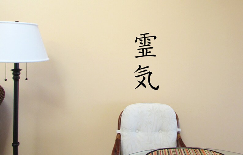 May include: A black and white wall decal with the Chinese characters for "important" and "air" in a vertical arrangement. The decal is on a beige wall with a white lamp and a white chair in the background.