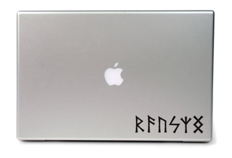May include: A silver laptop computer with a black apple logo and a black vinyl sticker with the text "RFNSYX" in a stylized font.