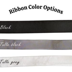 May include: Three horizontal ribbon strips labeled Ribbon Color Options. The top is a solid black grosgrain ribbon labeled Black. The middle is a sheer black tulle ribbon labeled Tulle black. The bottom is a sheer grey tulle ribbon labeled Tulle grey.