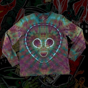 May include: A long-sleeved tie-dye shirt featuring an alien face design. The shirt's colors include purple, green, and blue, with a white outline of the alien's face. The shirt is made of a soft material and is suitable for casual wear.