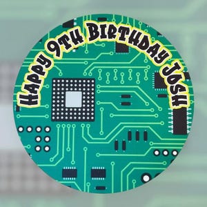 May include: A circular sticker featuring a green circuit board design. The text "HAPPY 9TH BIRTHDAY Josh" is printed in yellow and black, curving around the top and right side. The design has a digital, tech theme.