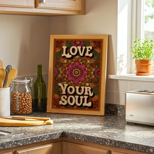 Puede incluir: Un estampado enmarcado con las palabras "LOVE YOUR SOUL" en una fuente retro. La obra de arte presenta un dise&ntilde;o floral de mandala en tonos de rosa, naranja y verde. El marco es de madera clara.