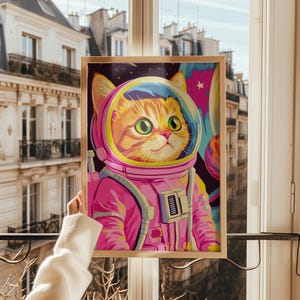 Funny orange cat wearing a pink astronaut suit in a colorful galaxy setting. This digital print combines pink poster aesthetics, dopamine decor energy, and girly prints charm. Ideal for fans of funny cat art, printable wall art, pink cat designs, and colorful wall arts. A playful coquette print perfect for cat lovers, space enthusiasts, and anyone who enjoys vibrant, happy decor.