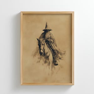 May include: A framed sepia print of a wizard on horseback. The wizard, wearing a tall hat and flowing robes, has a long beard. The artwork is set against a sepia background, within a light-coloured wooden frame.