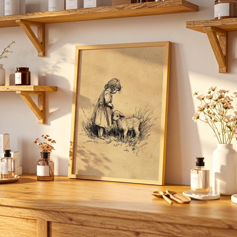 May include: A framed vintage-style print depicting a child and a lamb in a field. The artwork is a black and white sketch with a sepia-toned background, set in a light wood frame. The print is displayed on a wooden surface.
