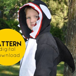 Puede incluir: Una sudadera con capucha negra y blanca con un diseño de orca rojo y blanco en la capucha. La sudadera tiene una aleta caudal negra unida a la espalda. El texto "PATTERN digital download" está en un círculo amarillo.