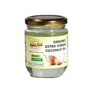 Puede incluir: Un tarro de vidrio con tapa dorada lleno de aceite de coco extra virgen orgánico transparente. La etiqueta es verde y blanca con el texto "Ceylan Foods" y "Organic Extra Virgin Coconut Oil". La etiqueta también indica "Non GMO" y "Gluten Free". El tarro está sobre un fondo blanco.