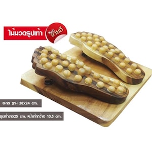 Peut inclure: Deux masseurs de pieds en bois avec des boutons ronds en bois, présentés sur une planche de bois. Les masseurs ont la forme de pieds et sont faits de bois clair et foncé. La base mesure environ 28 x 24 cm. Le masseur en forme de pied mesure 25 cm de long et 10,5 cm de large.