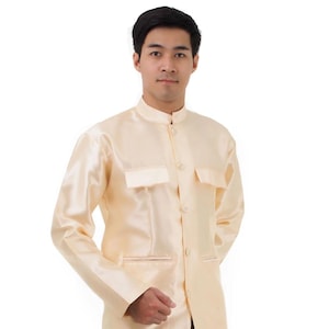 May include: A light beige, long-sleeved shirt with a mandarin collar and two chest pockets. The shirt has a satin-like sheen and a button-down front. The sleeves are long and the fit appears to be tailored.
