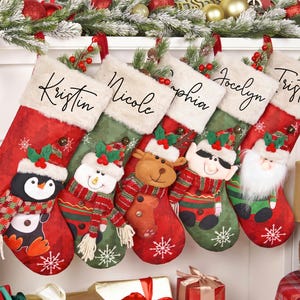 Puede incluir: Cinco calcetines navideños de tela roja y verde con puños de piel sintética blanca. Cada calcetín presenta un nombre personalizado en letra negra y un personaje de peluche: pingüino, muñeco de nieve, reno, elfo y Papá Noel con barba.