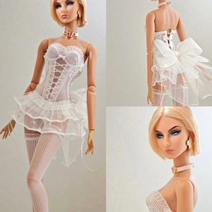 Op de afbeelding: Een modepop met blond haar en blauwe ogen, gekleed in een wit kanten korset, een gerokte rok en gestreepte kousen tot boven de knie. De pop heeft een delicate choker en oorbellen. De algehele esthetiek is elegant en vrouwelijk.