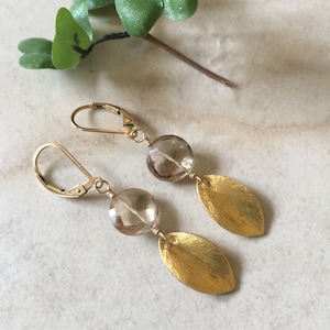 May include: Gold earrings with a brown gemstone and a leaf design.