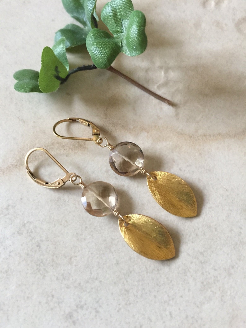 May include: Gold earrings with a brown gemstone and a leaf design.